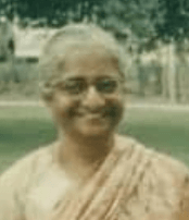 A smiling middle-aged South Asian woman, wearing a sari.