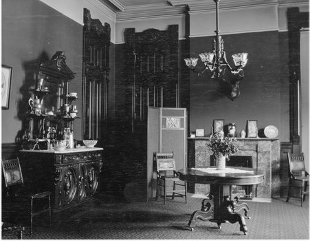 Room with a chandelier, table, sideboard and fireplace