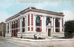 An old postcard of a library on a street corner, where a man is walking by with a top hat.