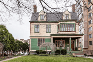 A picture of the Gallagher-Kieffer House in March 2020. The house is yellow and green, with a porch on the right side and decorative window panes.