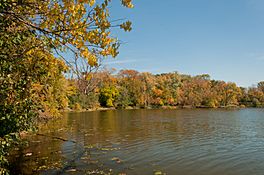 A lagoon, and trees with autumn colors behind it