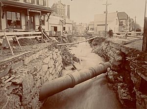 An open walled stream channel surrounded by wooden residential buildings