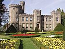 Victorian castellated mansion with a keep to the left and formal gardens in the foreground