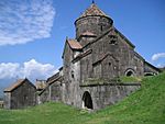 Small church of dark stone with a central tower topped by a conical roof.