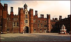 The courtyard of a red brick palace with tall chimneys and crenellations.