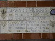 A tablet formed of five tiles of varying sizes, bordered by yellow and blue flowers in an art nouveau style