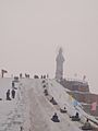 People sporting in snow by a statue of goddess Guanyin in Wujiaqu, Xinjiang