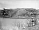 A monochrome photograph of the North Saskatchewn River with Fort Edmonton in the background