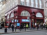 A red-bricked building with a sign reading "OXFORD CIRCUS HOUSE" in gold letters and a large number of people walking in the foreground