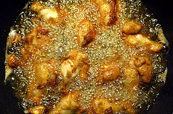 Battered chicken legs in bubbling oil.