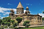 Stone church with a central tower topped by a conical roof and several smaller towers.