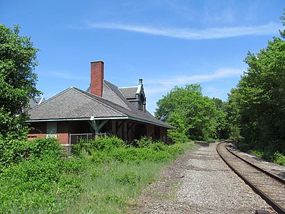 A brick railway station next to a single-track line