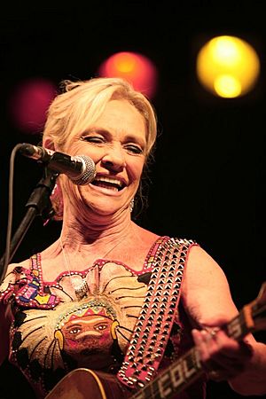 A woman sings and performs with a guitar