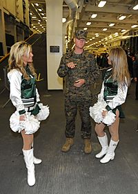 US Navy 091103-N-2147L-002 A Marine speaks with New York Jets cheerleaders aboard the amphibious transport dock ship Pre-commissioning Unit (PCU) New York (LPD 21). New York is New York is pierside in New York and will be comm