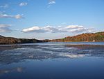 A reservoir in the foreground and forested mountain ridges with autumn leaves in the background