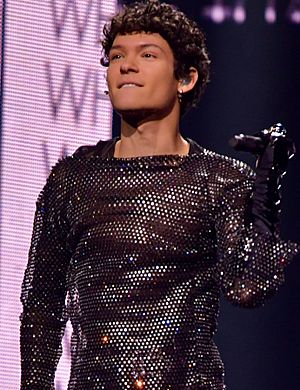 Omar Rudberg participating in Melodifestivalen 2022 wearing a black sequined outfit and black gloves.