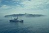 Lighthouse tender USCGC Fir at sea with the Cape Flattery Light, Washington, in the background.