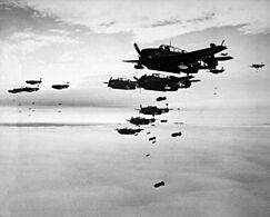 Photograph of a large number of propeller-driven monoplanes dropping bombs