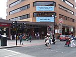 A red-bricked building with a rectangular, blue sign reading "Flexible Offices To Let 100 sq ft – 40,000 sq ft Meeting & Training Rooms"