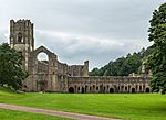 The ruins of a large abbey and church. The walls are mostly intact, though the roof has fallen in and been removed.