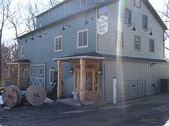 A brown building lined by wooden fence, lit sharply from the East by the early morning sun