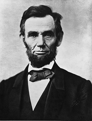 A monochrome photograph of a bearded man in a suit, showing his head and shoulders.