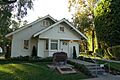 Photograph of the Richard M. Nixon Birthplace, a single-level, tree-shaded, white, wood-frame house.