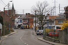 Photograph of a village, with a road on the center-left, a square in the middle, and a church in the background.