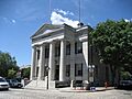 The front of a granite building, which has four columns supporting a triangular pediment.