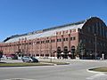 Exterior of a large arena with a semicircular roof curving over the building