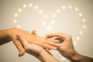 Man putting engagement ring on woman's finger