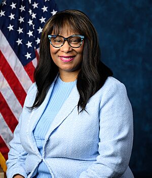 Official House portrait of Bynum smiling in front of the U.S. flag, wearing a light blue jacket and blue shirt.