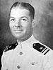 Head and shoulders of a white man with wavy hair, wearing a white military jacket with shoulder boards and a winged pin on the left breast.