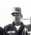 A black and white photograph of five men wearing Army uniforms and standing together as a group