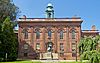 An ornate three-story brick building with a pedimented front section and tall gray cupola.