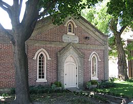 View of one-storey brick building in the shade of several mature trees