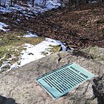 A large stone with a placard in the center, surrounded by a snow-covered lawn.