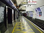 The interior of a building with a rounded ceiling and walls and a white sign hanging from the ceiling reading "Way out Central line"