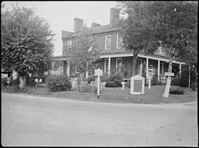 Black and white photo shows a two-story building.