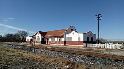 A building which is 195 feet (59 m) long and 26 feet (7.9 m) wide. The building architecture is eclectic, exhibiting both Spanish and Italian influences. The lower section of the exterior wall is brick, while there is covered with stucco. The stucco is painted white, decorated with tan painted trim. The center section has a gabled roof, with semicircular walls extending above the roof line on each end. The large window in the center is arched. Other windows have an arch design embedded in the stucco.