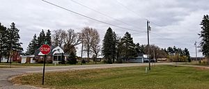 intersection of two two-lane roads with a stop sign and a few homes