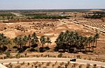 US Navy 030529-N-5362A-001 A U.S. Marine Corps Humvee vehicle drives down a road at the foot of Saddam Hussein's former Summer palace with ruins of ancient Babylon in the background.jpg