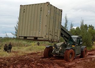 US Navy 070820-F-8678B-050 Construction Mechanic 1st Class Kenneth E. Terlaan drives a extendable boom forklift through the mud to position a CONEX box containing the field armory during setup for a field exercise