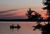 Two silhouetted people fishing on a boat