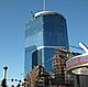 Ground-level view of an under construction 63-story building; The building's lower floors are covered in glass, but its upper 30 floors are unfinished and uncovered.