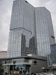 Ground level view of a 47-story building with a rectangular cross section and an all-glass facade; the building is still under construction, and a crane is visible on its roof.