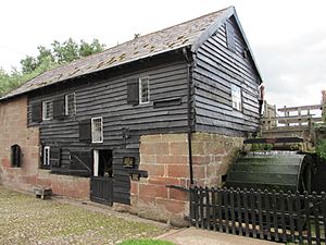 Stone mill building with weatherboarding and waterwheel to right