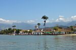 Plain with old buildings, forests, mountains and palm trees.