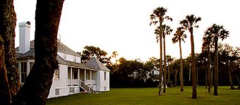 Photo of a sunset over a lawn featuring a large wooded area in the background