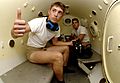 Photograph of the cramped interior of a cylinder containing two benches and two diver trainees